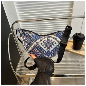 Detail of bohemian tapestry crossbody bag with colorful geometric woven pattern and black strap