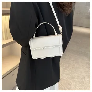 Detail of white wave-cut handbag showing the elegant gold hardware and top handle