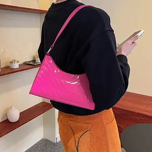 Glossy bright pink underarm bag with V-shaped quilting shown on a female model