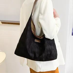 Grand sac cabas en toile matelassée noire avec anses en cuir marron porté par un mannequin