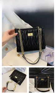Detail of black quilted shoulder bag featuring gold chain strap and metal twist lock