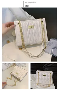 Detail view of off-white quilted shoulder bag with gold chain strap and turn-lock closure