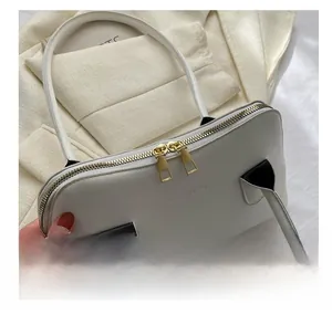 Détail d'un sac à main beige avec double fermeture éclair dorée et cuir synthétique grainé