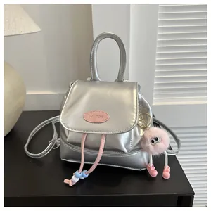 Close-up of metallic silver mini backpack with pink logo and cute plush charm detail