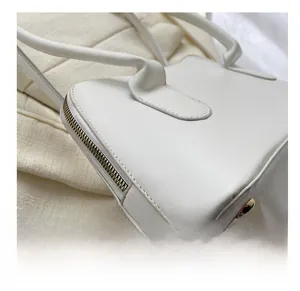Détail du bas du sac blanc avec clous dorés et coutures de bordure précises
