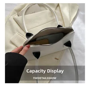 Vue détaillée de l'intérieur spacieux d'un sac à main blanc avec téléphone et portefeuille