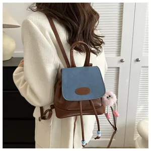 Mini denim and brown leather backpack with a pink plush toy hanging on the side