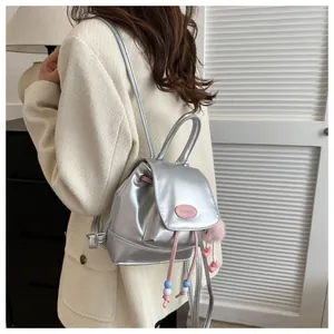 Close-up of a mini silver metallic backpack with pink beaded charms and brand name plate