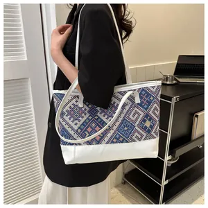 Détail d'un sac cabas ethnique tissé avec bandoulière en cuir blanc porté à l'épaule