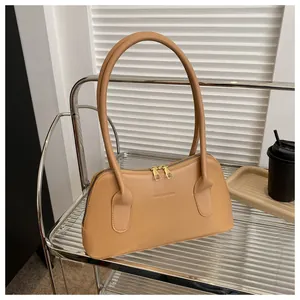 Détail du sac bandoulière en cuir camel avec double fermeture éclair dorée et logo
