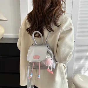 Chic silver PU leather mini backpack for women with a cute pink monster plush keychain