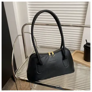 Détail d'un sac à main noir incurvé avec double fermeture éclair dorée et logo chic