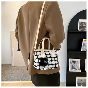 Détail du sac à carreaux avec poignée en cuir blanc et breloque monstre mignonne