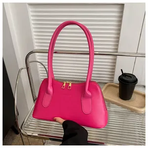Détail du sac à bandoulière en cuir mat rose vif avec double fermeture et logo imprimé