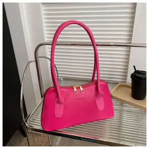 Détail du sac à bandoulière en cuir rose vif avec zip doré et logo gravé élégant