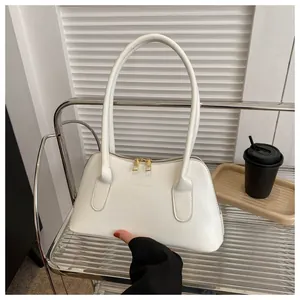 Détail macro du sac à bandoulière blanc avec fermetures éclair dorées et texte minimal
