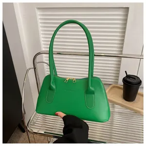 Vue détaillée du sac à main en cuir vert vif avec fermeture éclair dorée et texte embossé
