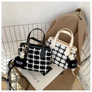 Gros plan de sacs à main en tweed à carreaux noir et blanc avec des charms en peluche