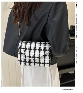 Detalle del bolso bandolera de tweed blanco y negro con cadena dorada en el modelo