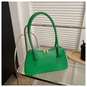 Détail du sac bandoulière en cuir vert vif avec double fermeture éclair dorée et gaufrage