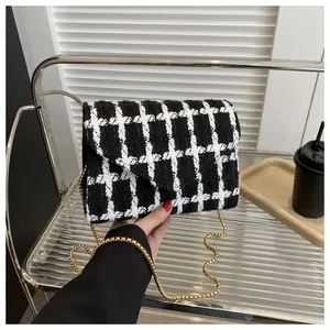 Detalle del bolso de tweed blanco y negro con textura tejida y cadena de metal dorado