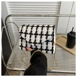 Detalle del bolso bandolera de tweed blanco y negro con cadena dorada y textura fina