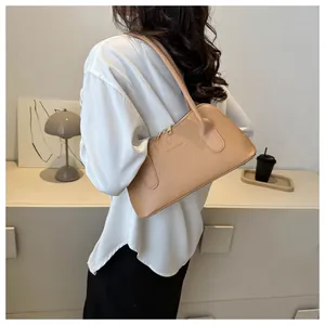 Gros plan du sac sous le bras en cuir kaki clair avec double bandoulière et zip doré