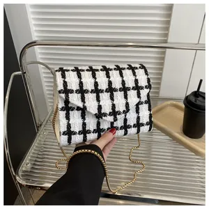 Detalle de patrón de cuadros de tweed blanco y negro con cadena dorada y solapa en V