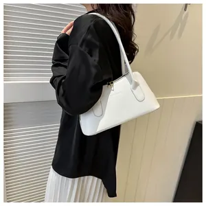 Détail d'un sac sous le bras en cuir blanc avec fines bretelles sur une épaule