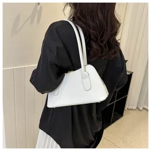 Vue détaillée d'un sac à bandoulière blanc minimaliste porté par un mannequin élégant