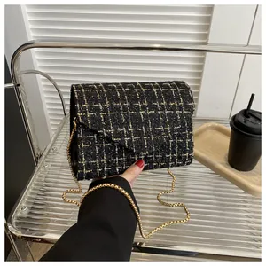 Vista detallada de la textura de tejido de tweed negro y dorado en un bolso de cadena