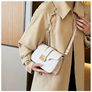 Close-up of a white quilted crossbody bag with a gold clasp on a beige trench coat