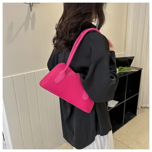 Détail du sac à bandoulière rose vif en cuir avec de longues anses et une texture lisse