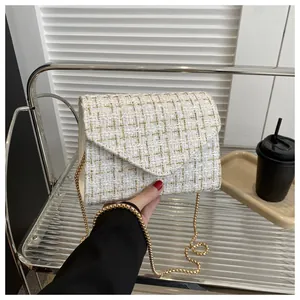Detalle del bolso sobre de tweed blanco con hilos dorados y elegante correa de cadena