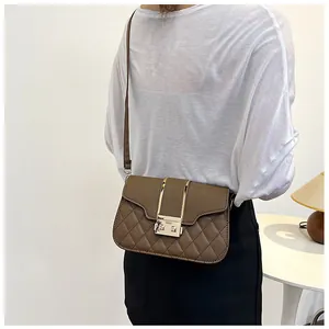 Detail of dark brown quilted crossbody bag with gold metal bars and twist lock closure
