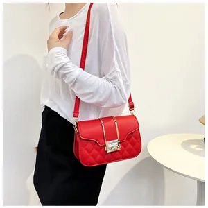 Detail of red quilted faux leather shoulder bag with adjustable strap and metal clasp