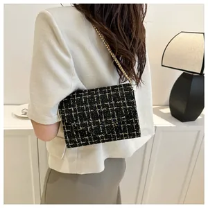 Detalle de bolso bandolera de tweed con cadena dorada visto desde un ángulo lateral