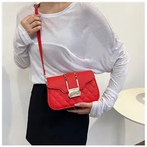 Detail of red quilted crossbody bag with golden metal buckle worn by a model
