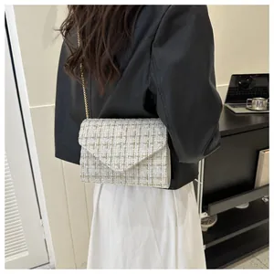 Detalle de bolso bandolera de tweed blanco con cadena dorada y textura elegante