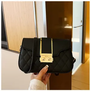 Detail of black quilted shoulder bag with golden metallic lock and matte leather texture
