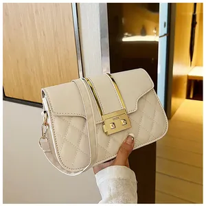 Detail of cream quilted crossbody bag with golden rectangular clasp and metal accents