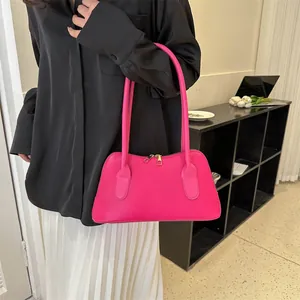 Sac sous le bras rose vif tendance en similicuir lisse porté par un mannequin chic