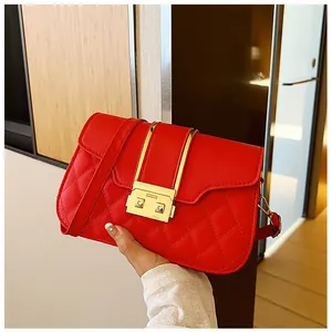 Close-up of red quilted leather crossbody bag with golden square lock and metal accents