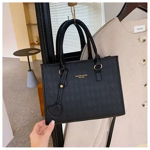 Detail view of black quilted PU leather tote bag with gold logo and heart charm
