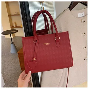 Detail of red quilted leather handbag featuring gold logo and heart-shaped pendant