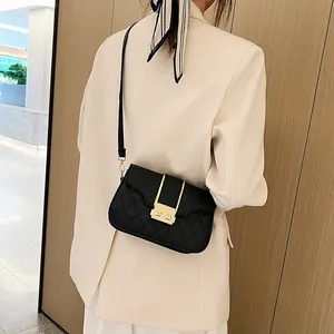 Chic black quilted crossbody bag with gold buckle on model in beige blazer