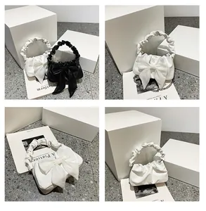 Dettaglio borsa alla moda con fiocco, manici arricciati e catena in metallo chic