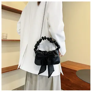 Dettaglio del manico arricciato e fiocco in tulle su borsa vintage nera a tracolla