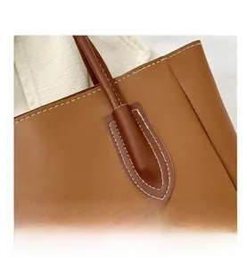 Close-up of caramel brown pebble leather tote bag showing white contrast stitching detail