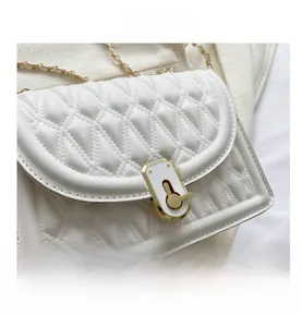 Detail of white quilted handbag featuring gold metal chain and twist-lock closure